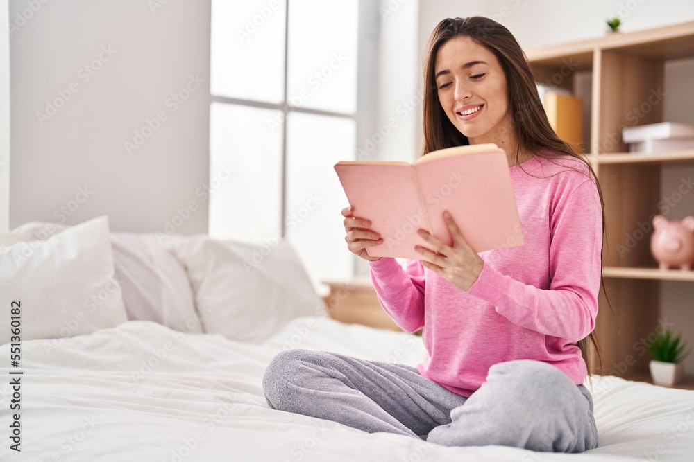 Young beautiful hispanic woman reading book sitting on bed at bedroom Young beautiful hispanic woman reading book sitting on bed at bedroom