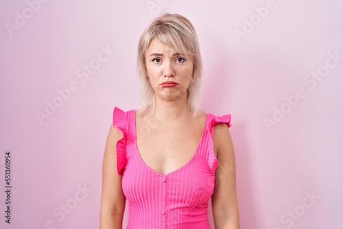 Young caucasian woman standing over pink background depressed and worry for distress, crying angry and afraid. sad expression.