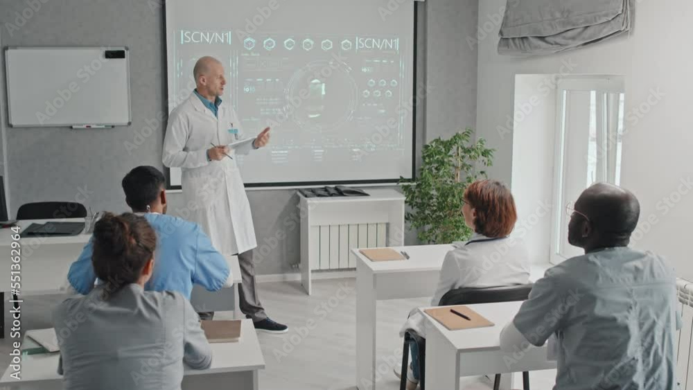 Modern mature Caucasian doctor holding digital tablet making presentation of new medical technology or treatment method