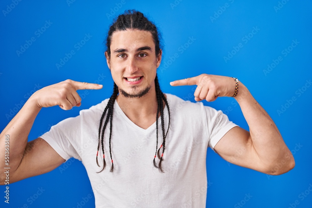 Hispanic man with long hair standing over blue background smiling cheerful showing and pointing with fingers teeth and mouth. dental health concept. Hispanic man with long hair standing over blue background smiling cheerful showing and pointing with fingers teeth and mouth. dental health concept.