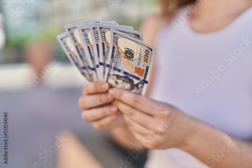Young woman holding dollars at park