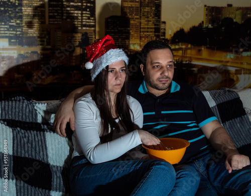 Adult girl and guy are watching TV, eating popcorn. Selective focus. Picture for website about family, leisure.