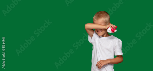 Boy has covered his eyes with his hand and is holding crumpled paper. Protest, fatigue, training, coercion, discontent, disobedience, upbringing, denial. Selective focus.