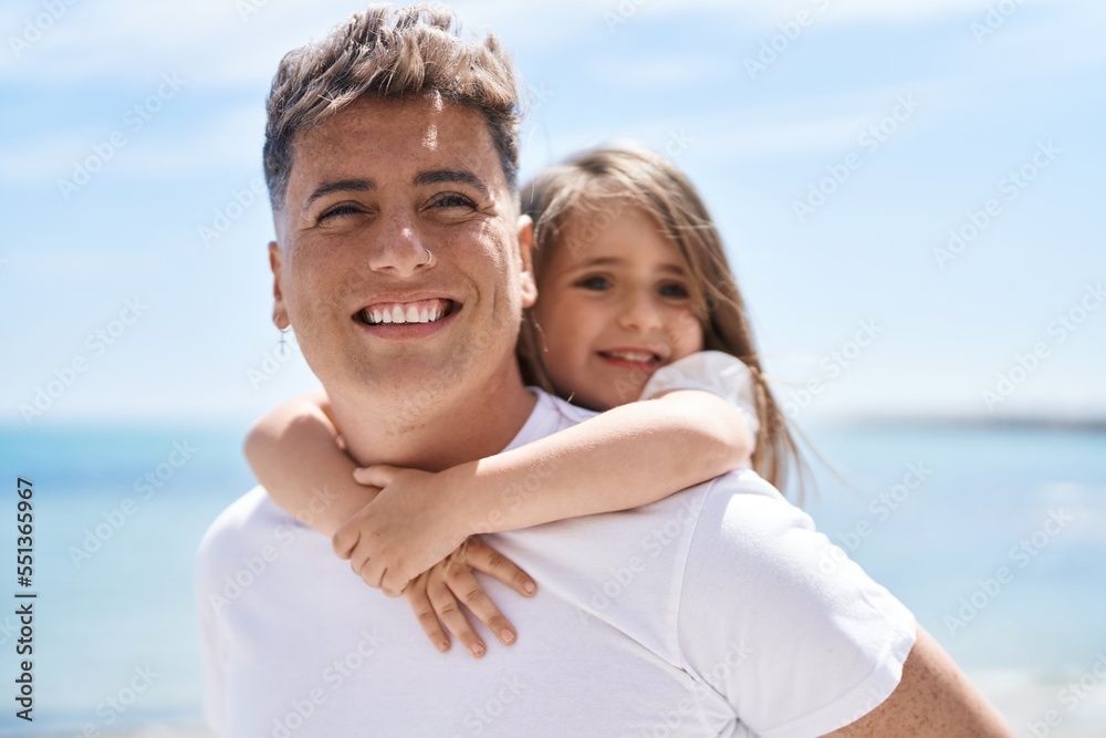 Father and daughter smiling confident hugging each other holding on back at seaside