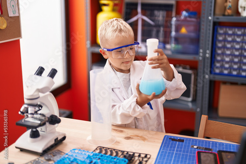 Adorable toddler student holding test tube at classroom