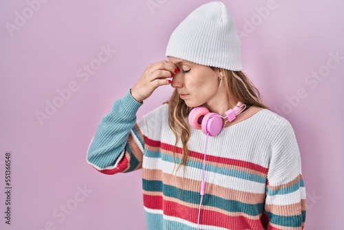 Young blonde woman standing over pink background tired rubbing nose and eyes feeling fatigue and headache. stress and frustration concept.