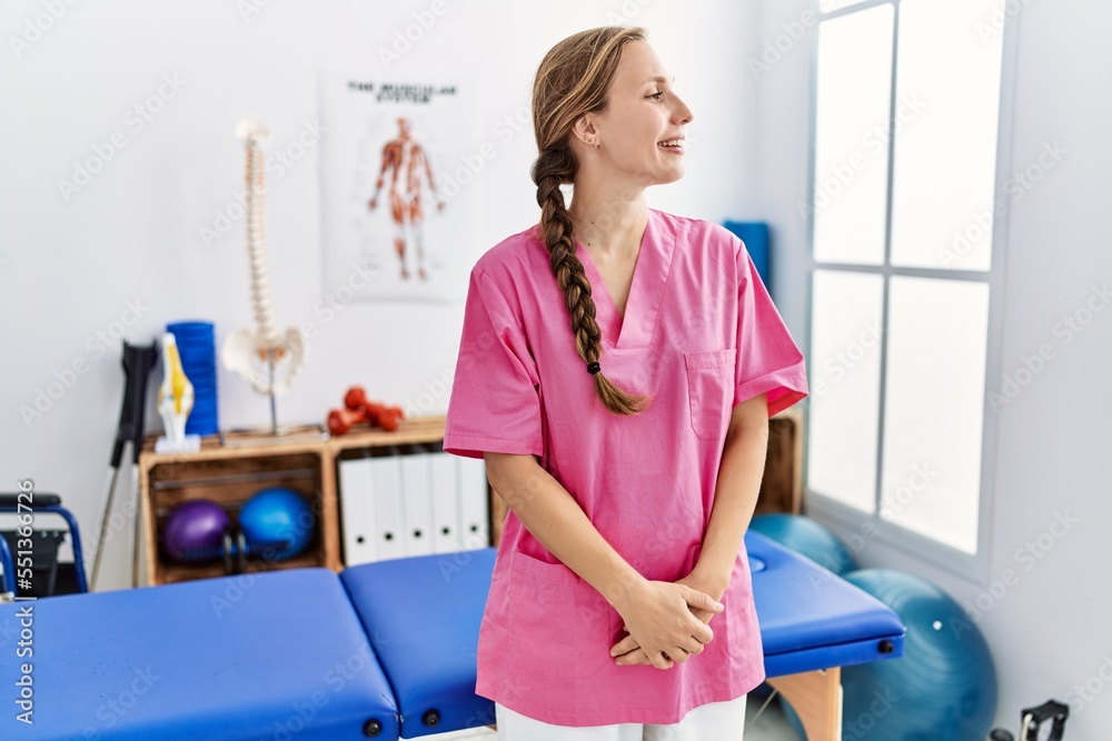Young blonde woman working at pain recovery clinic looking away to side with smile on face, natural expression. laughing confident. Young blonde woman working at pain recovery clinic looking away to side with smile on face, natural expression. laughing confident.