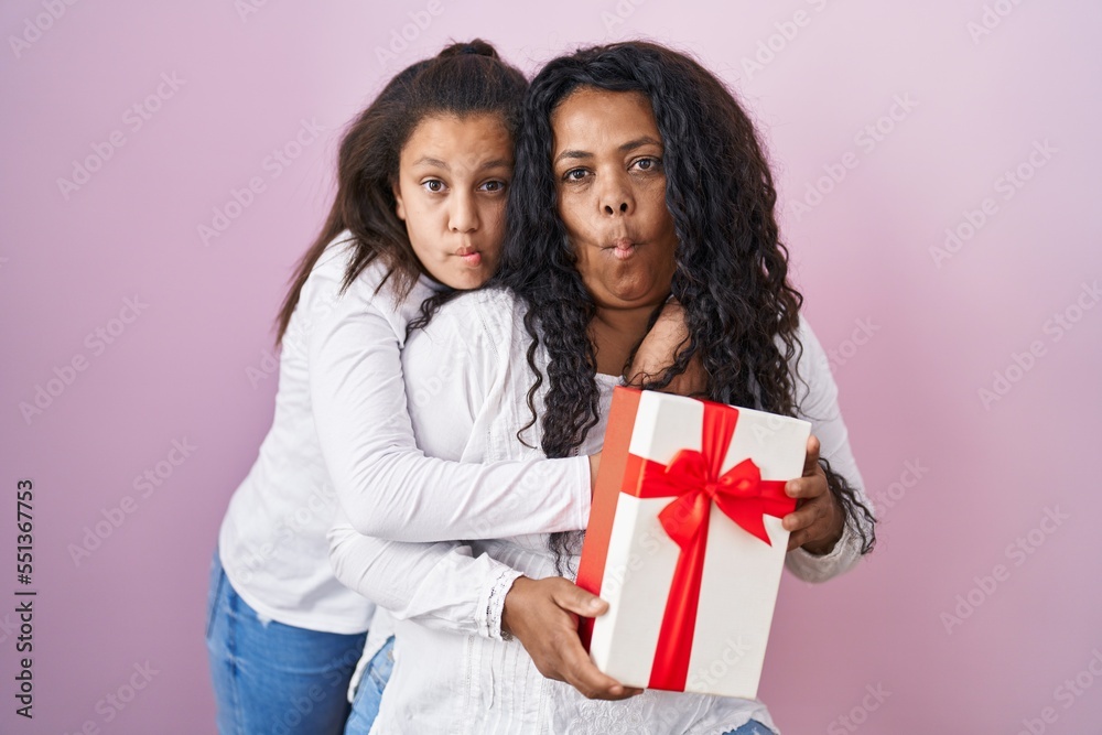 Mother and young daughter holding with presents making fish face with mouth and squinting eyes, crazy and comical. Mother and young daughter holding with presents making fish face with mouth and squinting eyes, crazy and comical.