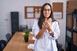 Young hispanic woman at the office suffering pain on hands and fingers, arthritis inflammation