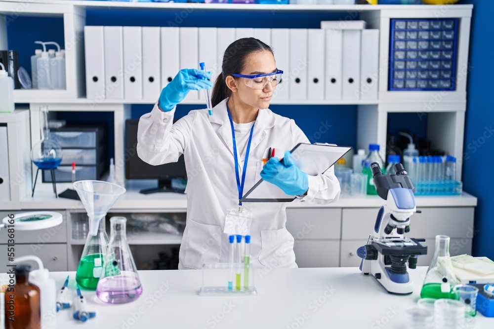 Young hispanic woman scientist holding test tube at laboratory Young hispanic woman scientist holding test tube at laboratory