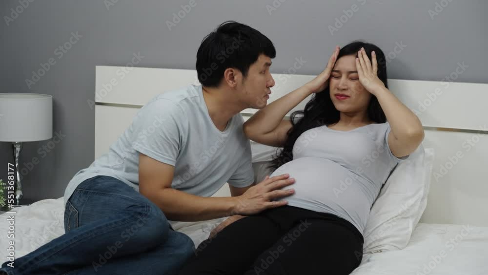 pregnant woman having headache with her husband on a bed pregnant woman having headache with her husband on a bed