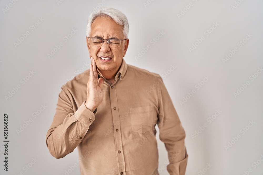 Hispanic senior man wearing glasses touching mouth with hand with painful expression because of toothache or dental illness on teeth. dentist Hispanic senior man wearing glasses touching mouth with hand with painful expression because of toothache or dental illness on teeth. dentist