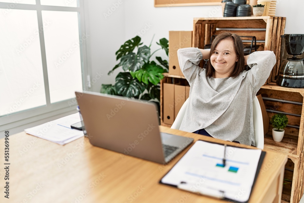 © Krakenimages.com - Brunette woman with down syndrome stretching arms relaxing at business office