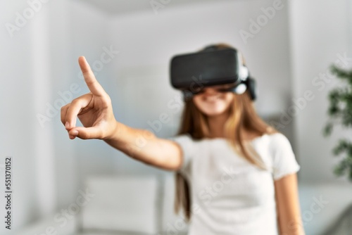 Adorable girl playing video game using vr goggles at home