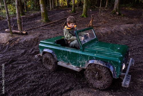 A Teen ride in an open iron children's car. Extreme form of entertainment for children. The boy drives through the mud in the forest. High quality photo