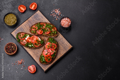 Tasty bruschetta with tomatoes, mozzarella, basil, spices and herbs