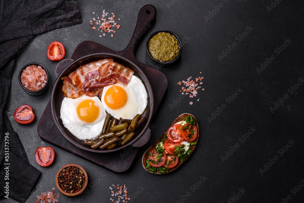 Tasty breakfast consists of eggs, bacon, beans, tomatoes, with spices and herbs Tasty breakfast consists of eggs, bacon, beans, tomatoes, with spices and herbs