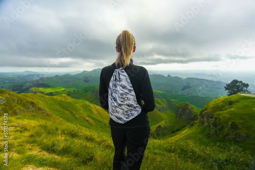 Female hiker standing on peak enjoying view of green Te Mata landscape in New Zealand