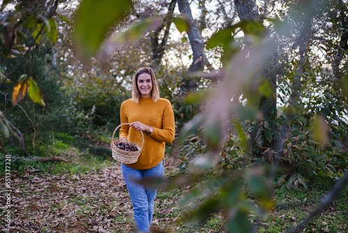 Woman carrying a wicker basket with many chestnuts collected on an autumn afternoon