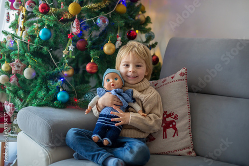 Cute toddler child. boy, hugginh baby puppy corgi dog at home on Christmas photo