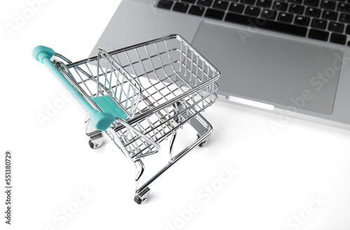 miniature shopping cart from a store stands next to a laptop. selective focus 