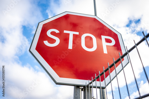 Closeup photo of a stop sign by a fence.