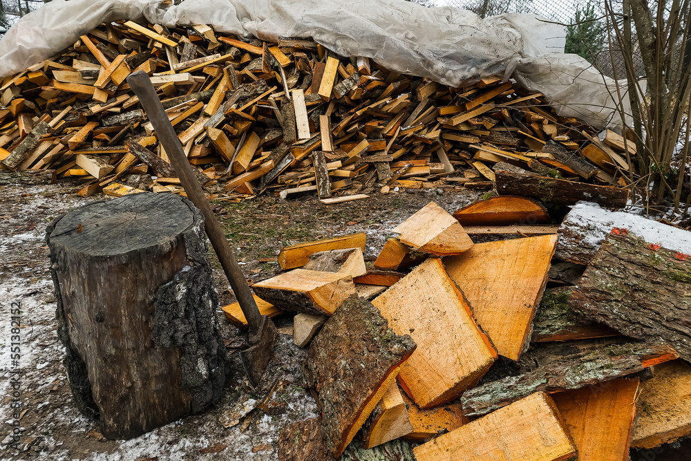 A pile of firewood for heating a house. Wooden block with an axe. A pile of firewood for heating a house. Wooden block with an axe.