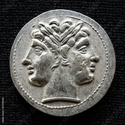Ancient coin showing two-headed Roman god Janus, 225-214 BC. Vintage money isolated on black background. photo