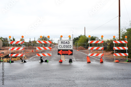 Street closed sign and detour arrow with white and orange striped barricades photo