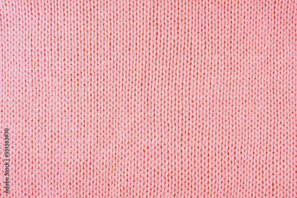 Close up background of knitted wool fabric made of viscose yarn. Pastel red color wool knitwear texture. Abstract knitted jersey background. Fabric abstract backdrop, wallpaper