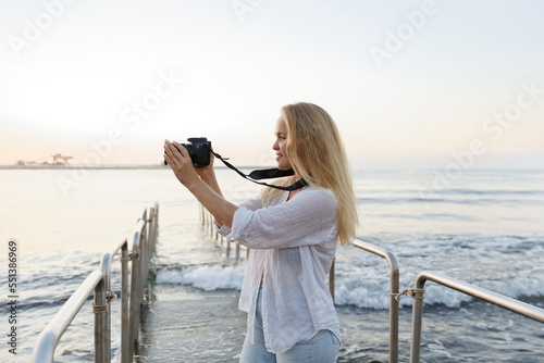 Photographer, woman and camera at beach for travel vacation or holiday in summer sun.
