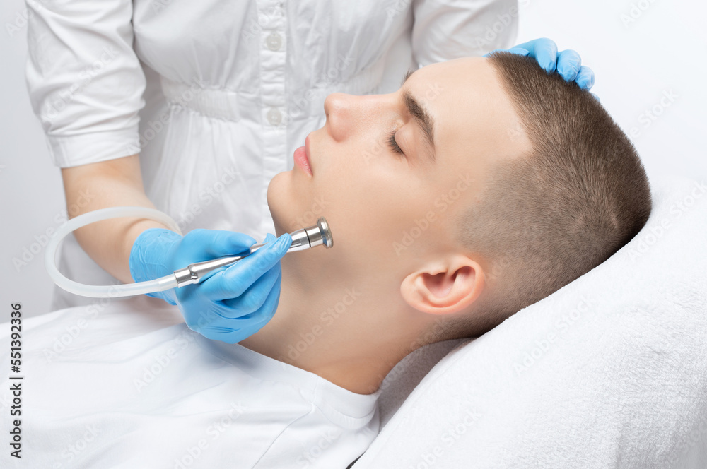 A cosmetologist is making the procedure Microdermabrasion of the facial skin in a beauty salon. Cosmetology for men and professional skin care. A cosmetologist is making the procedure Microdermabrasion of the facial skin in a beauty salon. Cosmetology for men and professional skin care.