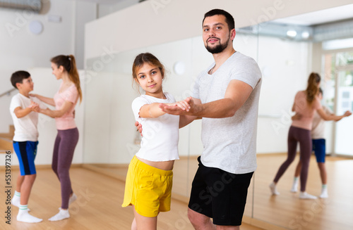 Young girl dancing with her dad during rehearsal in gym.