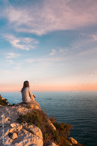 Young woman watching the sea during sunset