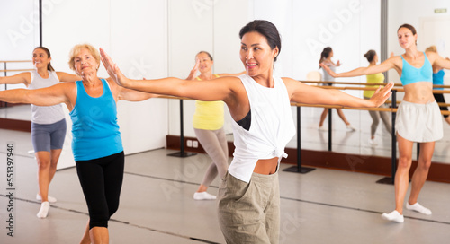 Portrait of a positive Asian woman enjoying energetic dancing in a female group in a modern dance studio