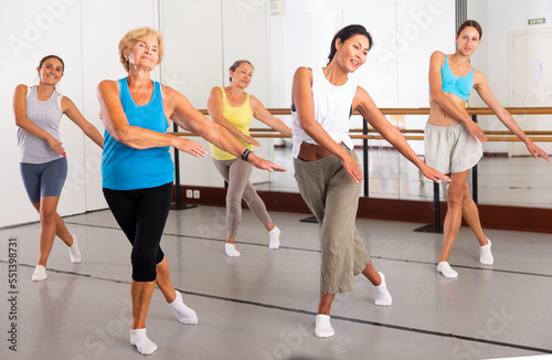 Active women engaged in dancing at a group training session in the studio practice modern energetic dance