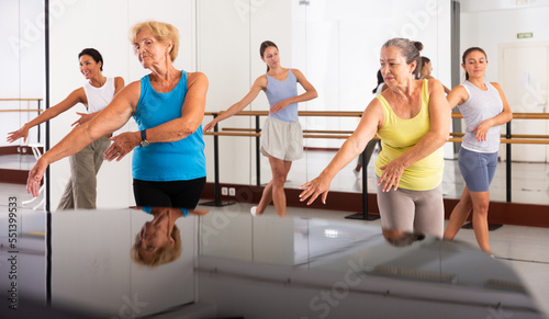 Active women engaged in dancing at a group training session in the studio practice modern energetic dance