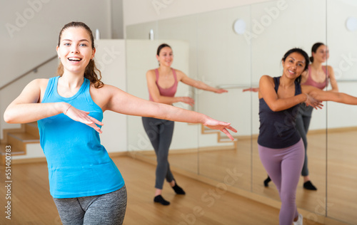 Portrait of cheerful girl practicing vigorous jive movements in group dance class.
