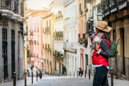 a tourist woman wearing a cap and backpack, walks through the streets of the historic center of Madrid. Walking tourism in spain. Concept of tourism and Spanish culture.