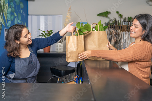 Cheerful seller giving shopping bags with plants to customer