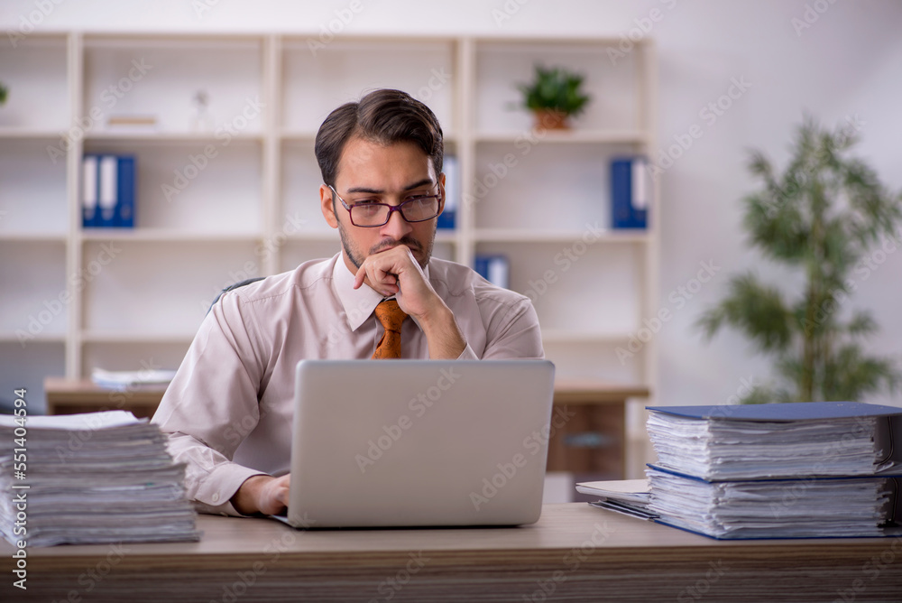 Young male employee and too much work in the office Young male employee and too much work in the office