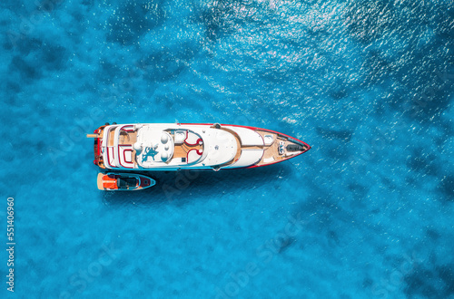 Aerial view of beautiful luxury yacht and boat in blue sea at sunset in summer. Sardinia island, Italy. Top view of speed boat, sea coast, transparent water. Travel. Tropical landscape. Yachting  © den-belitsky