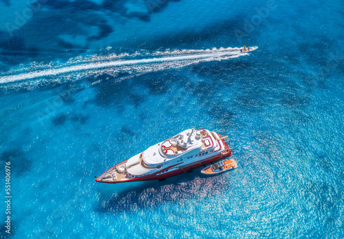 Aerial view of beautiful red luxury yacht and boat in blue sea at sunset in summer. Sardinia island, Italy. Top view of speed boat, sea coast, transparent water. Travel. Tropical landscape. Yachting  photo