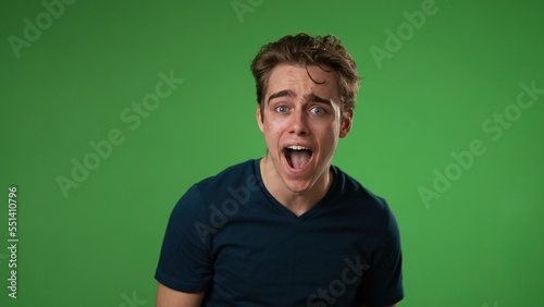 Portrait of amazed young man 20s shocked, saying WOW . Handsome guy surprised isolated on solid green screen background.