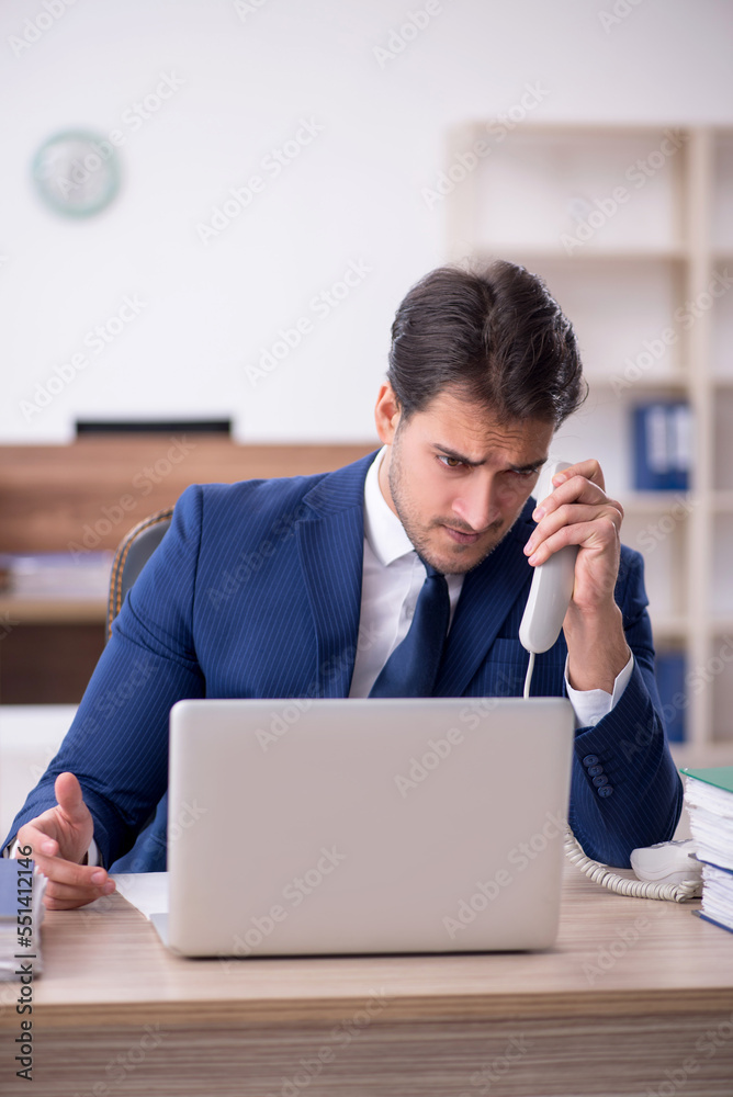 Young male employee and too much work in the office Young male employee and too much work in the office