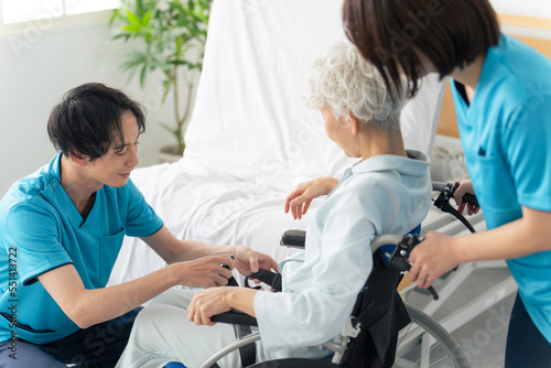 高齢者を介護ベッドから車椅子に移乗させる介護士 photo