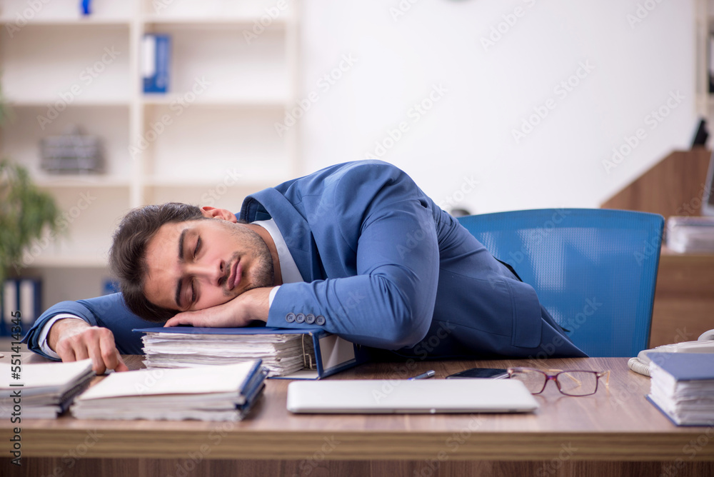 Young male employee unhappy with excessive work in the office Young male employee unhappy with excessive work in the office