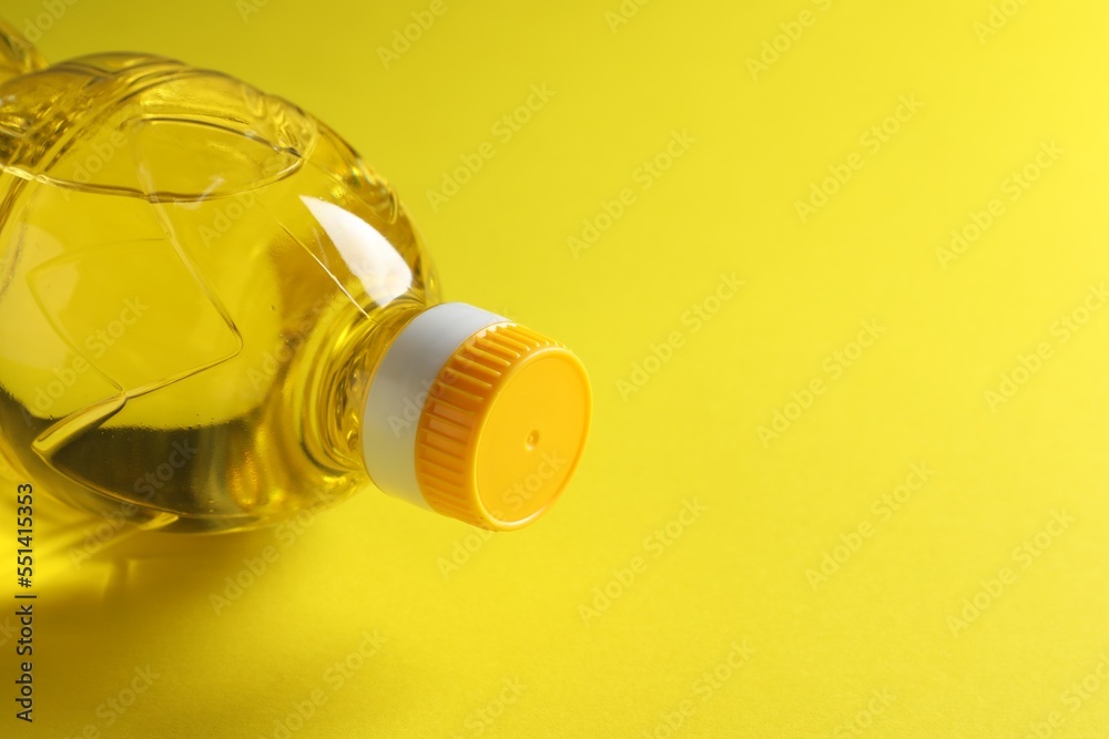 Plastic bottle of cooking oil on yellow background. Space for text Plastic bottle of cooking oil on yellow background. Space for text