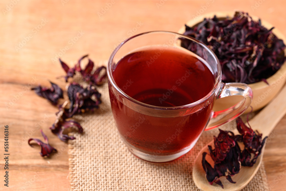 Roselle tea in cup glass with dry roselle on wooden background, Herbal drink for reduction in blood pressure Roselle tea in cup glass with dry roselle on wooden background, Herbal drink for reduction in blood pressure