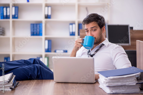 Young male employee unhappy with excessive work at workplace